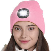 Pink beanie with a built-in flashlight worn by a model on a white background