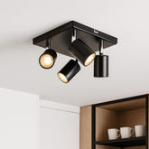 Black ceiling light fixture with three cylindrical lights on a white ceiling.