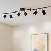 Black ceiling track light fixture with six spotlights on a white ceiling.