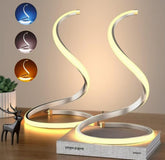 Modern table lamp with curved design on a wooden surface, featuring color options above it.