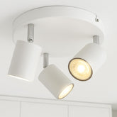 White ceiling light fixture with three cylindrical shades on a white background