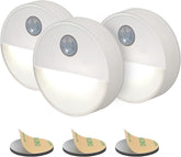 Three motion sensor lights with adhesive pads on a white background