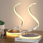 Modern table lamp with curved design on a wooden surface