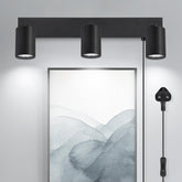 Modern wall-mounted light fixture with three cylindrical lights on a neutral background.