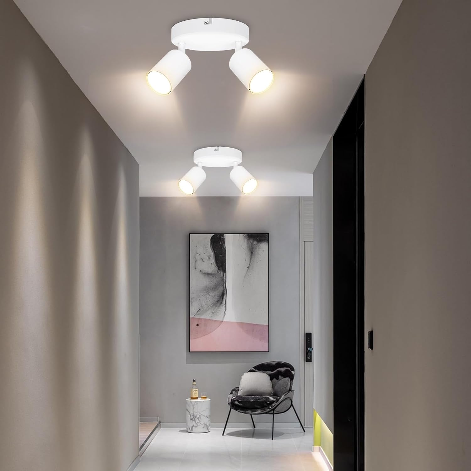 Modern hallway with ceiling lights, a chair, and a painting on a gray wall.
