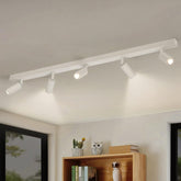 Track lights on a ceiling with a bookshelf and decor items below