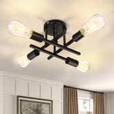 Modern black ceiling light fixture with four lit bulbs in a room.