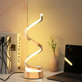 Modern spiral table lamp on a desk with a laptop and plant