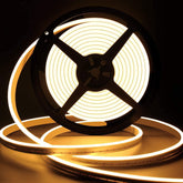 Spool of LED strip light with warm glow on a dark background