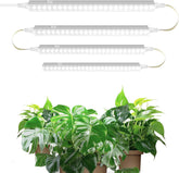 Set of LED grow lights above potted plants on a white background