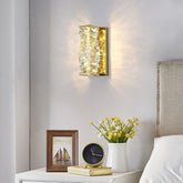 Decorative wall sconce on a wall with a nightstand featuring a clock, photo frame, and vase with flowers.