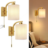 Gold wall sconces with white lampshades on a white background and in a room setting.