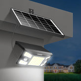 Solar-powered outdoor light fixture with a solar panel on a wall, glowing in the dark.