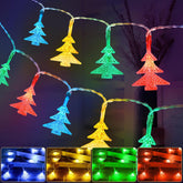String lights shaped like Christmas trees in red, green, blue, and yellow on a dark background.