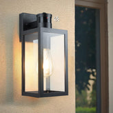Black outdoor wall light fixture on a textured wall with a blurred background