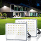 Two LED flood lights in front of a modern house at night.