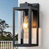 Black outdoor wall light fixture on a white wall with a clear glass cover.