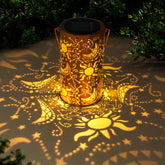 Decorative solar lantern casting patterns on the ground with greenery around.