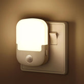 Beige night light with motion sensor on a wall switch plate, glowing softly.