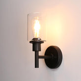 Black wall-mounted light fixture with clear glass shade on a plain background