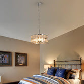 Chandelier hanging above a bed in a bedroom with striped bedding and decorative pillows.