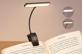 Clip-on book light on an open book with a neutral background