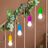 Colorful string lights with white bulbs hanging on a railing against a brown wall.
