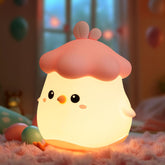 Cute chicken-shaped night light with a soft glow on a fluffy surface.