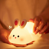 Cute rabbit-shaped night light being held by a person with a warm glow.