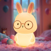 Cute rabbit-shaped night light with glasses on a soft surface with colorful eggs.