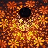 Decorative lantern with floral patterns casting shadows on a wall