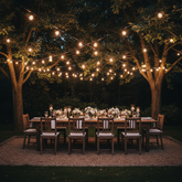 Dining table set under string lights in a garden at night