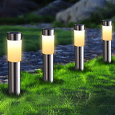 Four solar-powered garden lights on grass with a blurred natural background