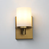 Gold wall sconce with a white glass shade on a light gray background