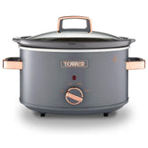 Gray slow cooker with rose gold handles and control knob on a white background