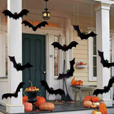 Halloween decorations on a porch with pumpkins and bats.