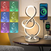 Modern LED table lamp with multiple color options displayed, charging phone and smartwatch on a table.