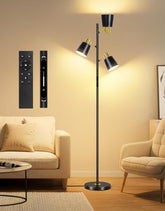 Modern floor lamp with three light fixtures in a living room setting, accompanied by remote controls.