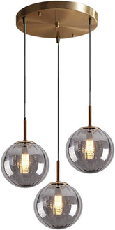 Modern pendant light fixture with three glass shades and gold accents on a white background