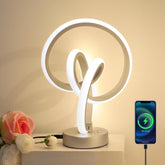 Modern table lamp with smartphone charging cable on a neutral background