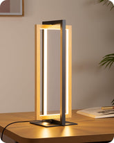 Modern table lamp with wooden frame and black base on a wooden surface.