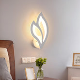 Modern wall light fixture on a wall with a vase of flowers and a mirror in the foreground.