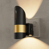 Modern wall light fixture with black and gold design on a gray wall.