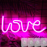 Neon sign spelling 'love' on a dark background with decorative elements