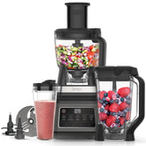 Ninja blender with ingredients and a smoothie on a white background