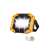 Orange and black portable floodlight with USB cable on a white background