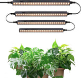 Set of LED grow lights above potted plants on a white background