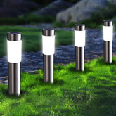 Set of four outdoor solar lights on grass with a blurred natural background