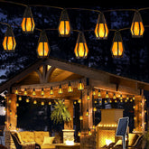 String lights hanging above a wooden gazebo with outdoor furniture at night.