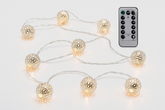 String lights with decorative bulbs and a remote control on a light gray background